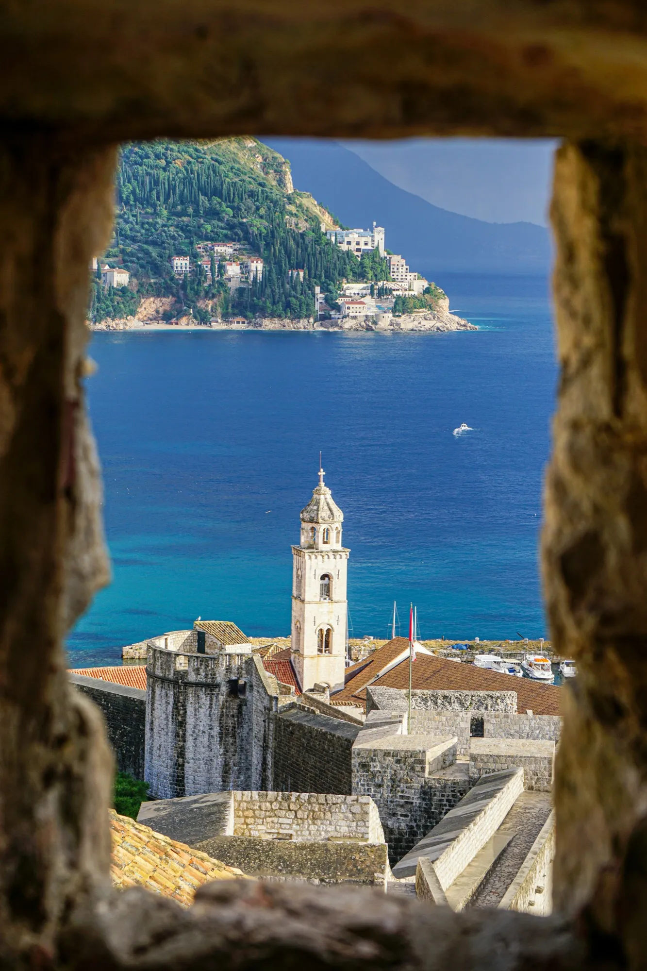 Dubrovnik bell tower and the sea framed by a stone window in the city walls